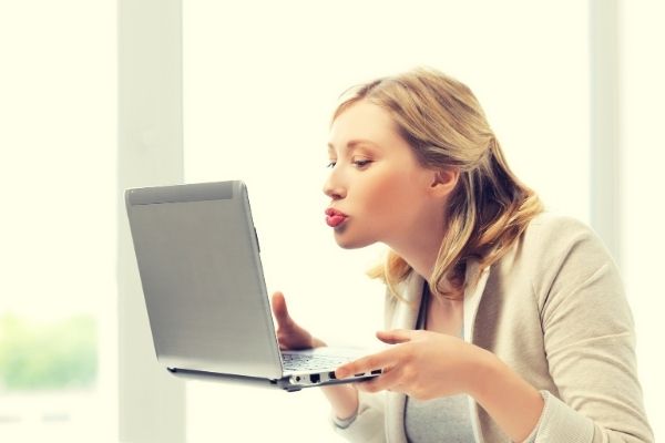 woman blowing a kiss to computer showing connection